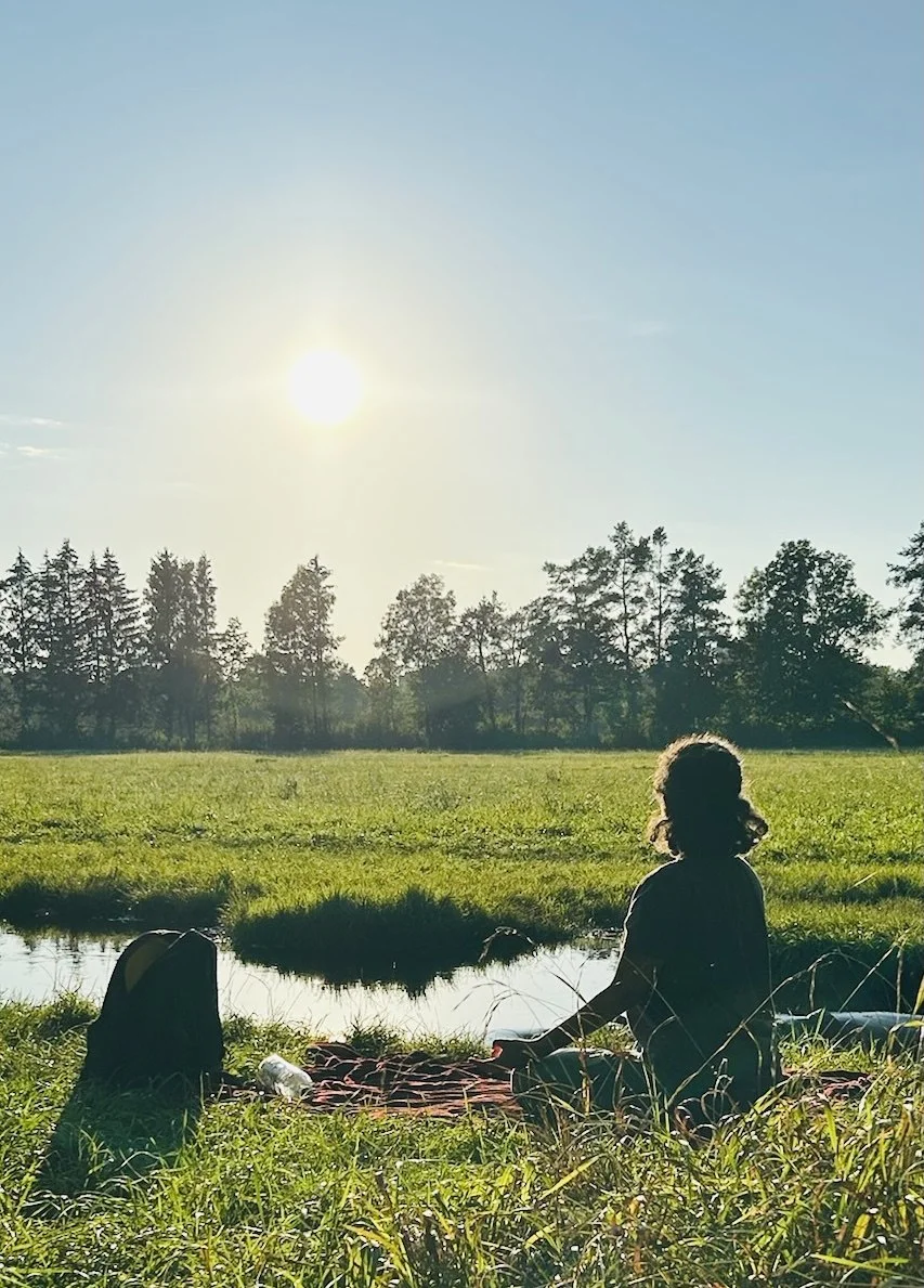Sahar sitzt bei Sonnenuntergang auf einer Wiese